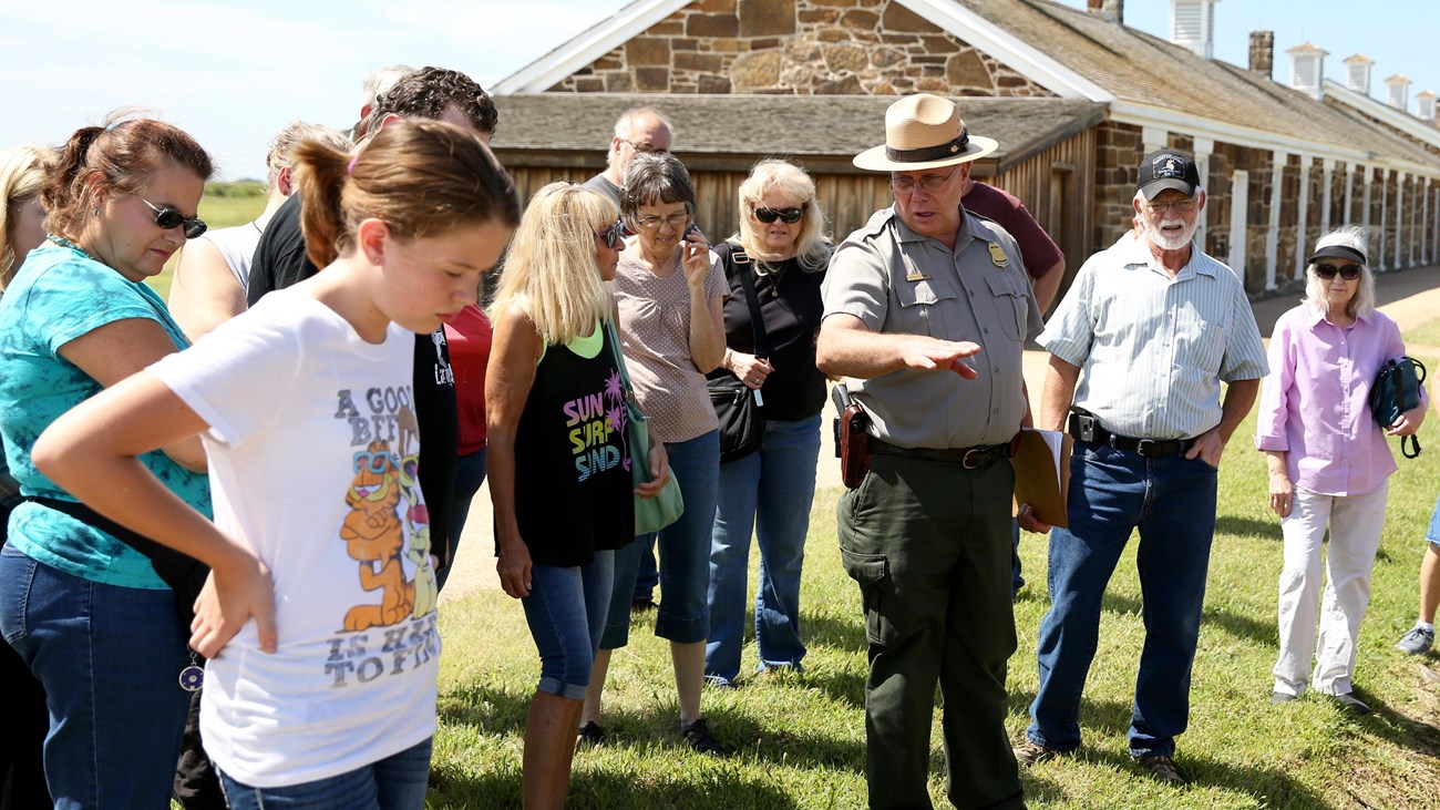 People standing around park ranger in uniform who is talking