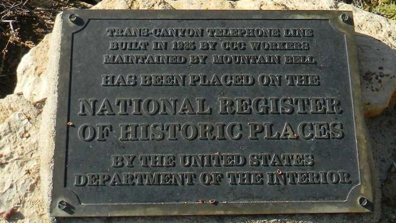 A bronze plaque set into rough limestone looks over the canyon edge.