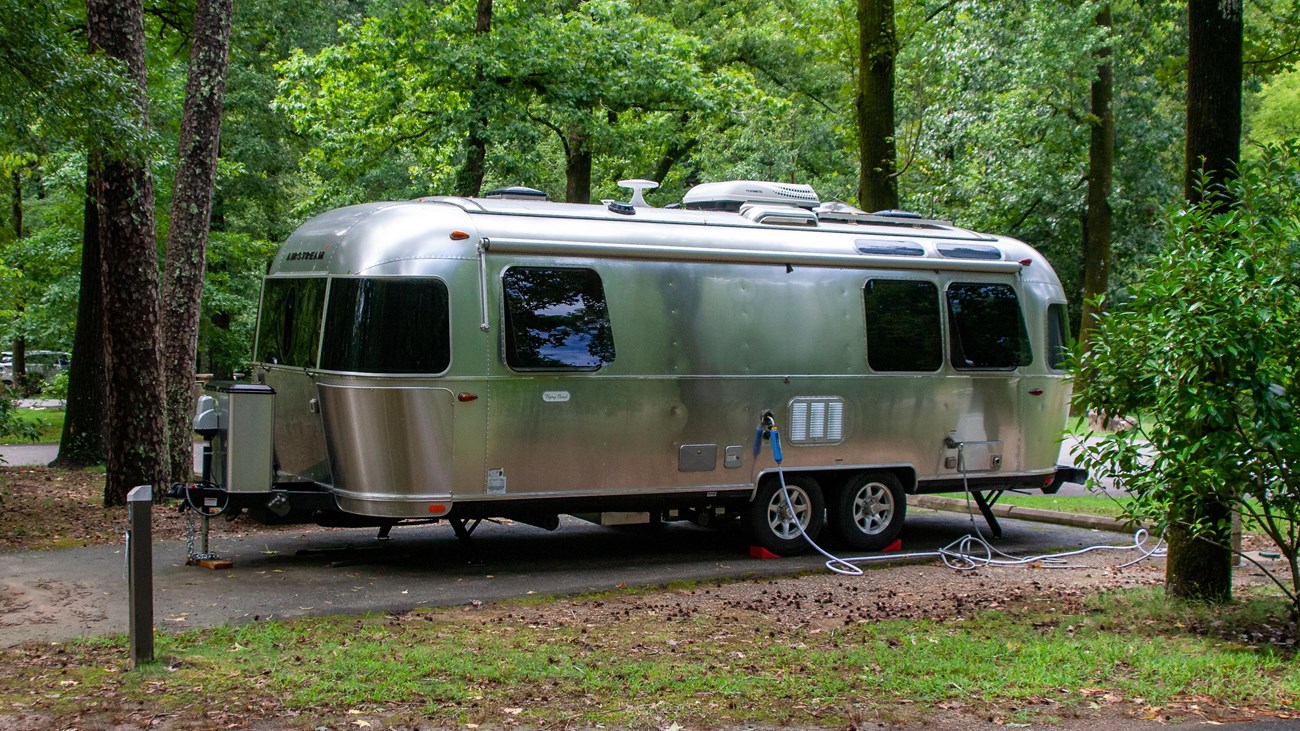 RV parked at campsite in the woods.