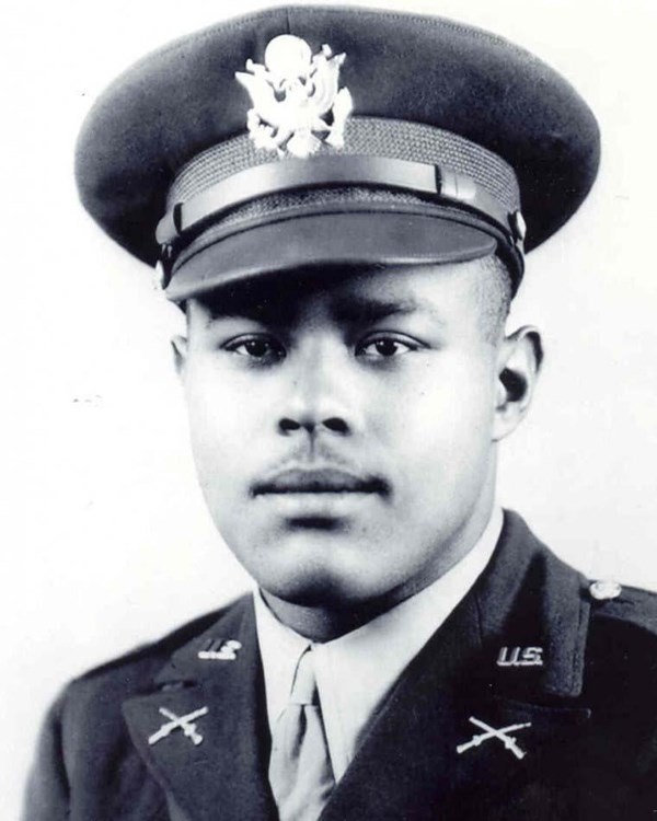 Black and white photo of African American man in World War Two hat and uniform looking at camera.