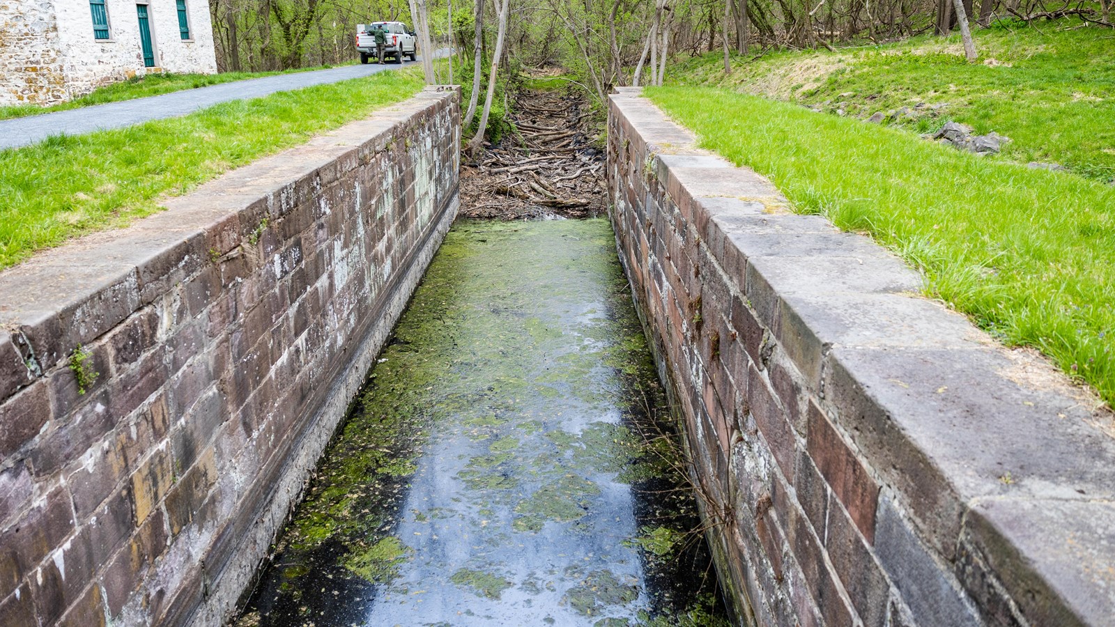 An historic stone lock with water next to a lockhouse