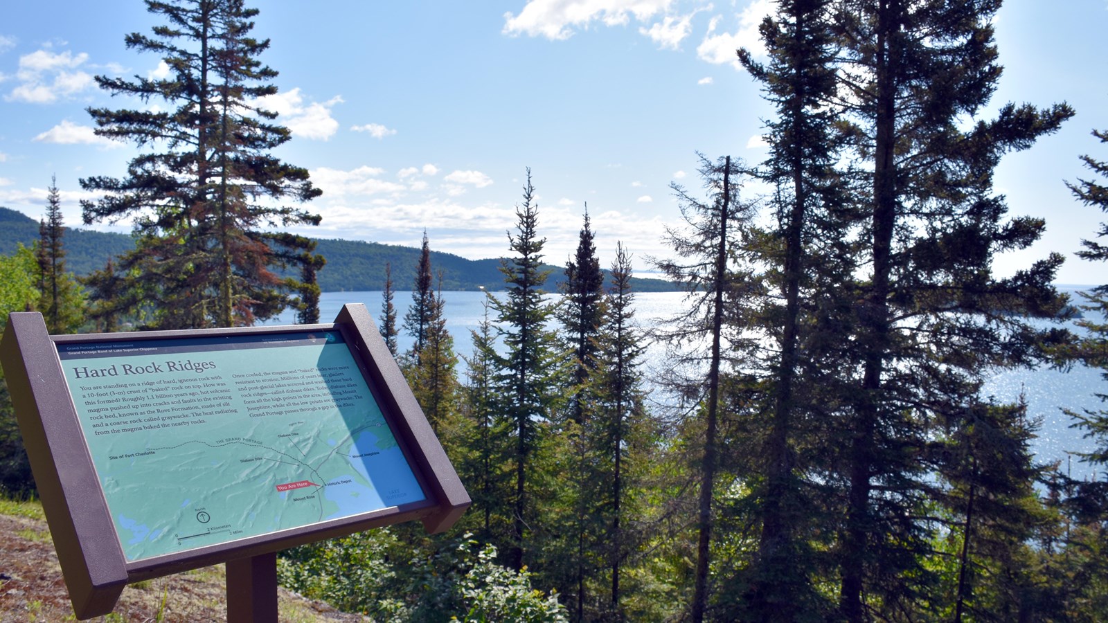 Interpretive wayside in front of a peninsula at the edge of a bay.