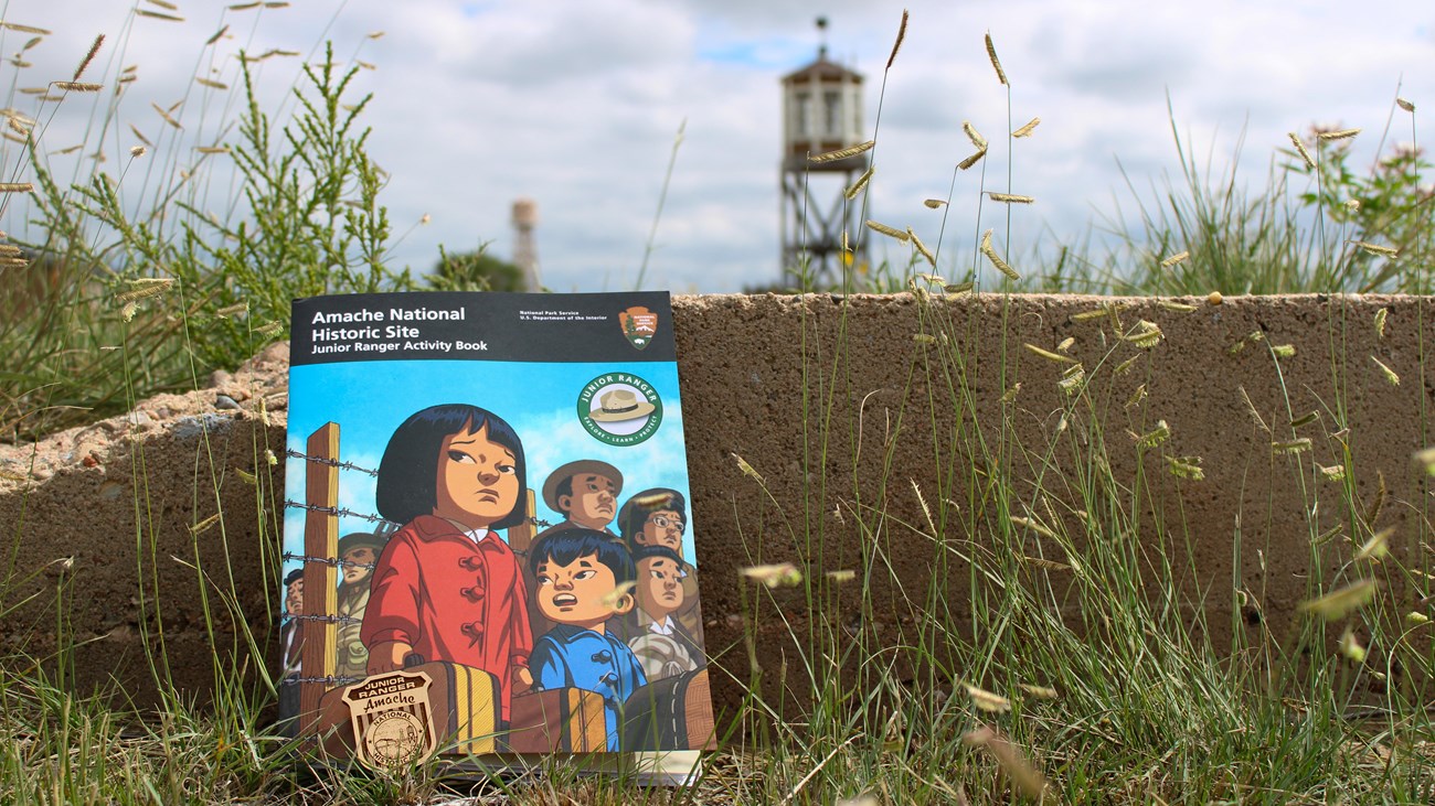 A booklet with two cartoon children on the cover leans against a concrete foundation