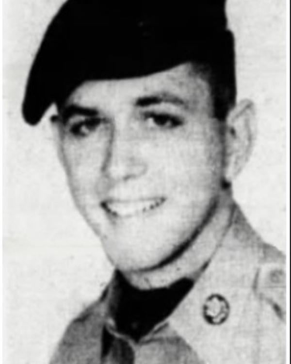 Young man dressed in U.S. Military uniform with hat and smiling for photo. 
