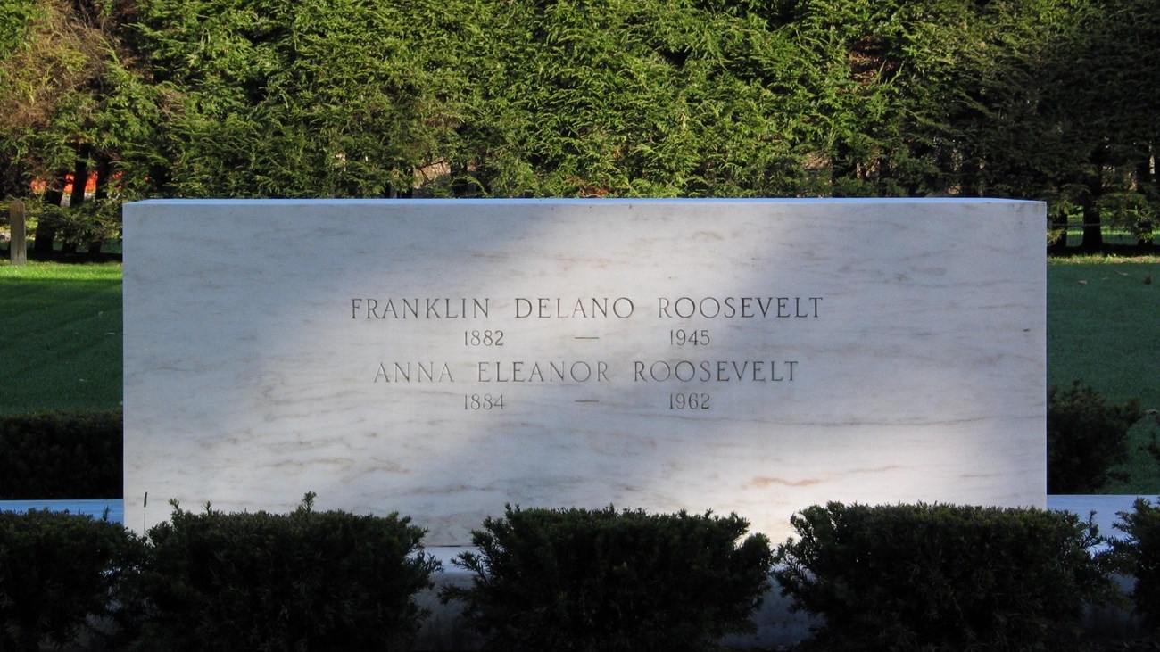 A large marble block engraved with the names and life dates of Franklin and Eleanor Roosevelt.