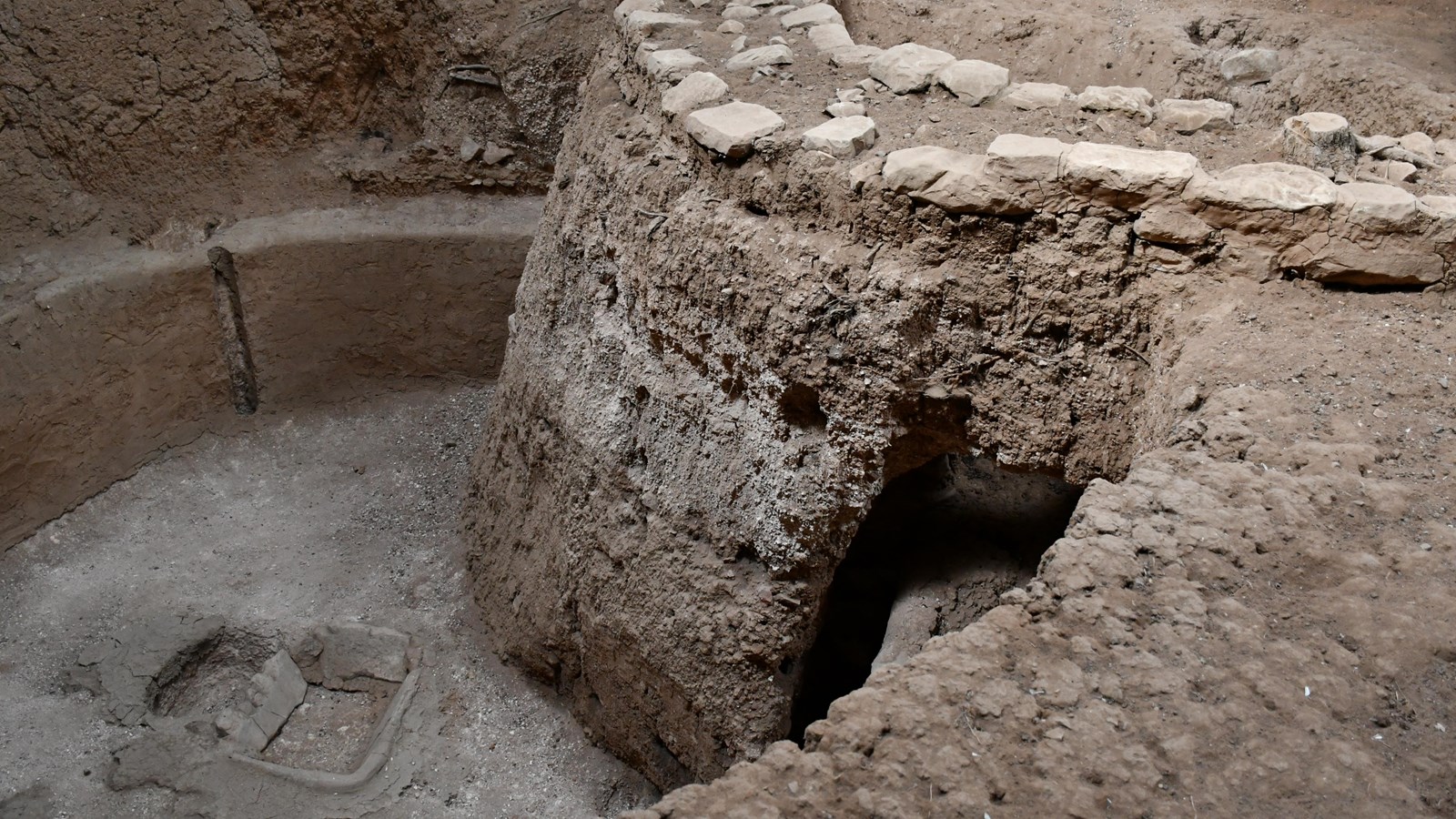 The stone walls of a pueblo village overlap an older pithouse structure.