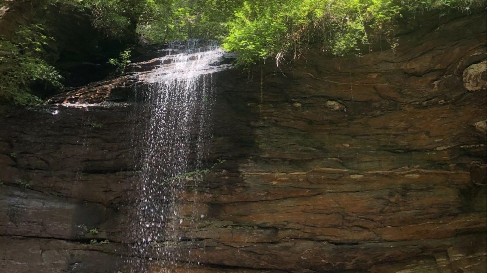 A narrow waterfall cascades over a rocky cliff edge.
