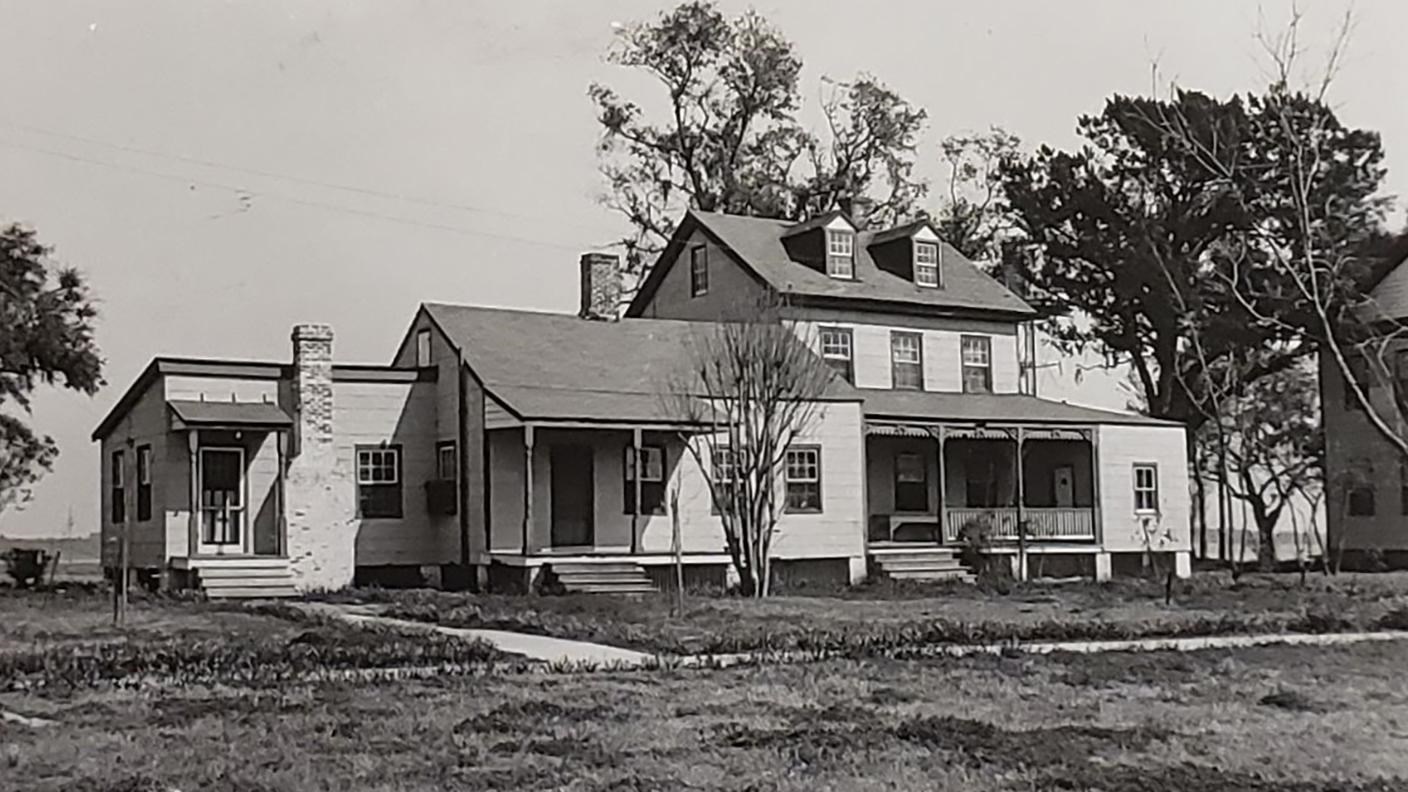 A two story cottage with multiple additions and a front porch.