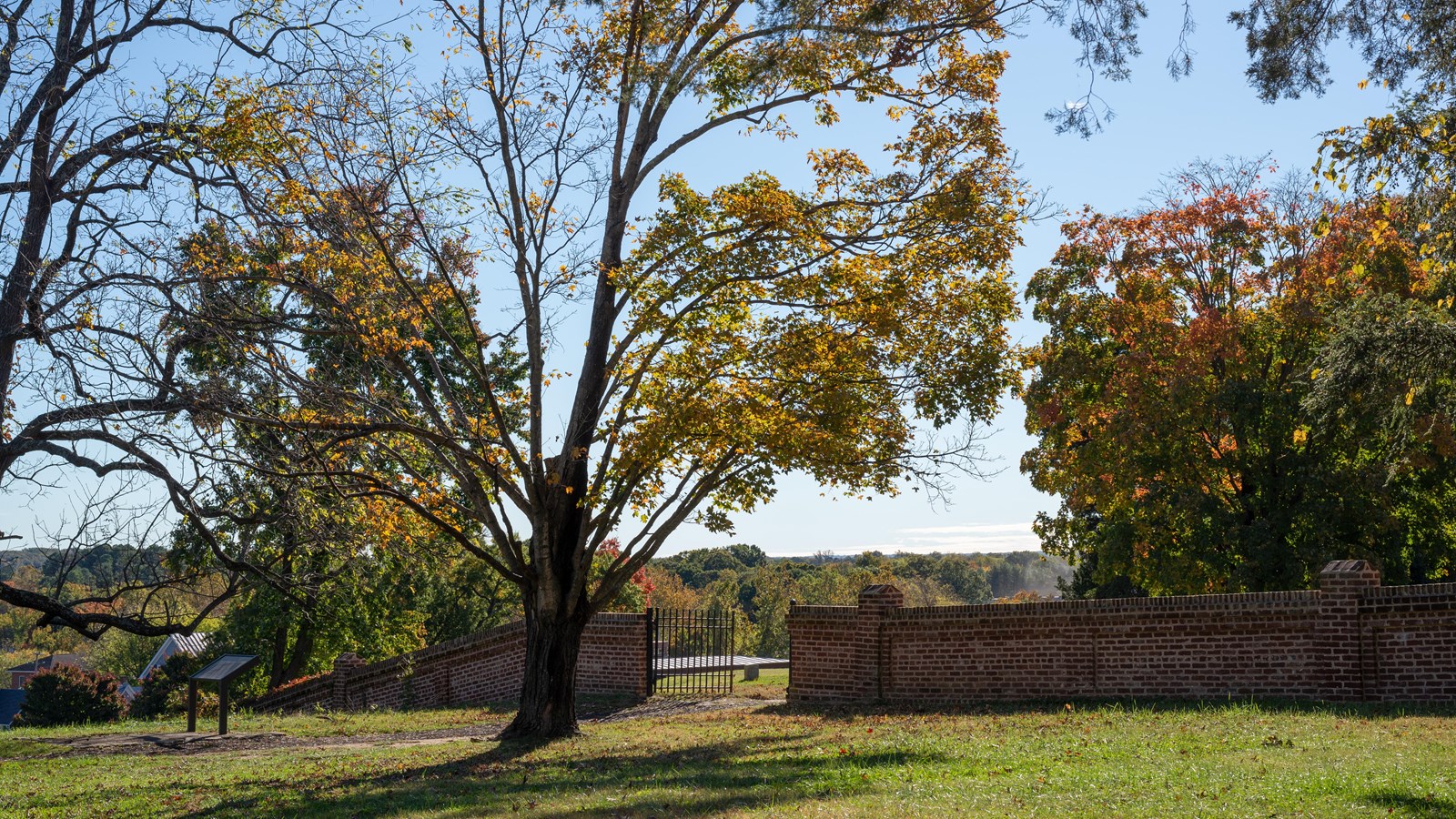 Fall scene of a brick wall across a field.