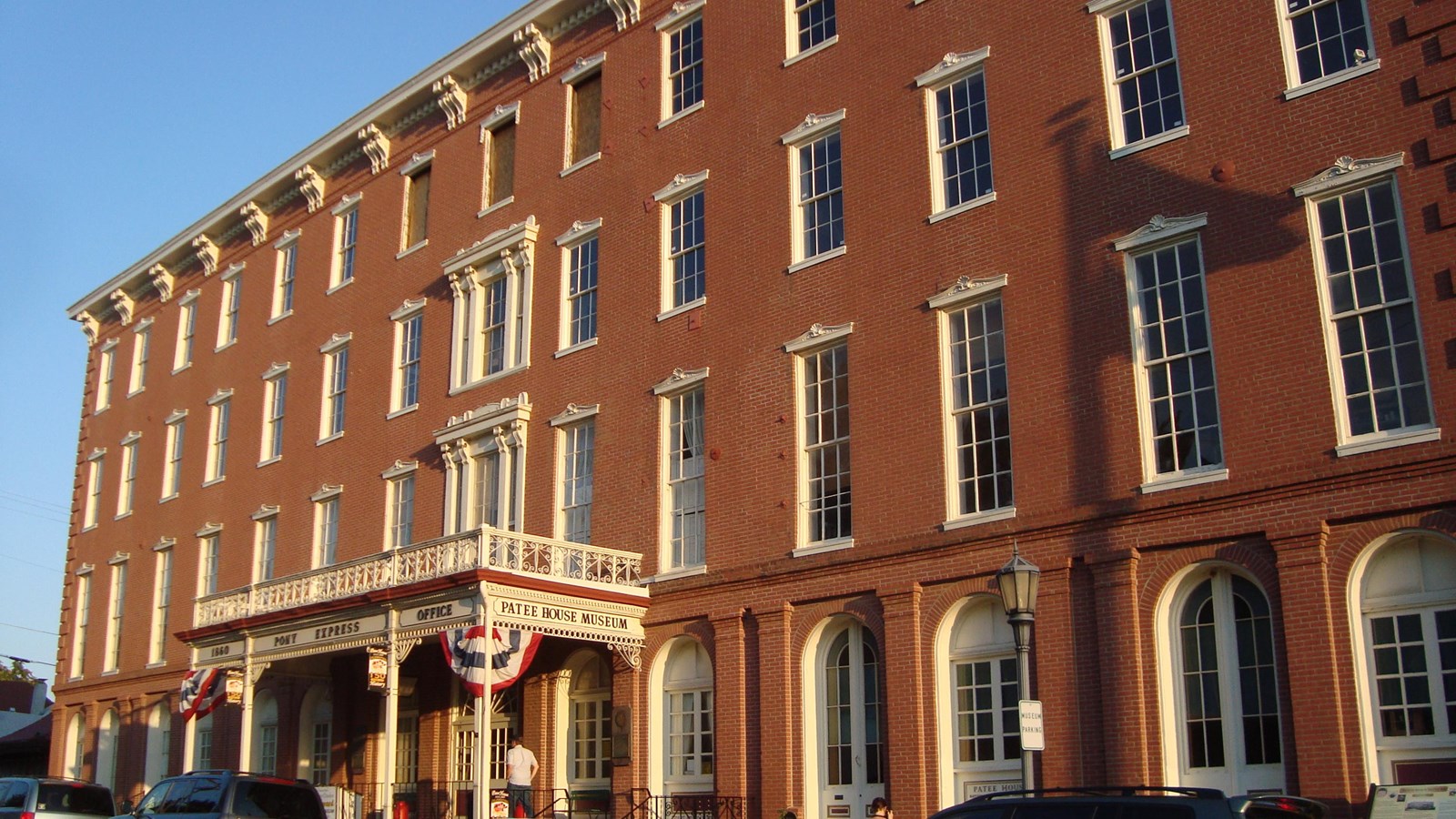 Morning sun casts a golden glow over the front of Patee House, with red, white and blue bunting.