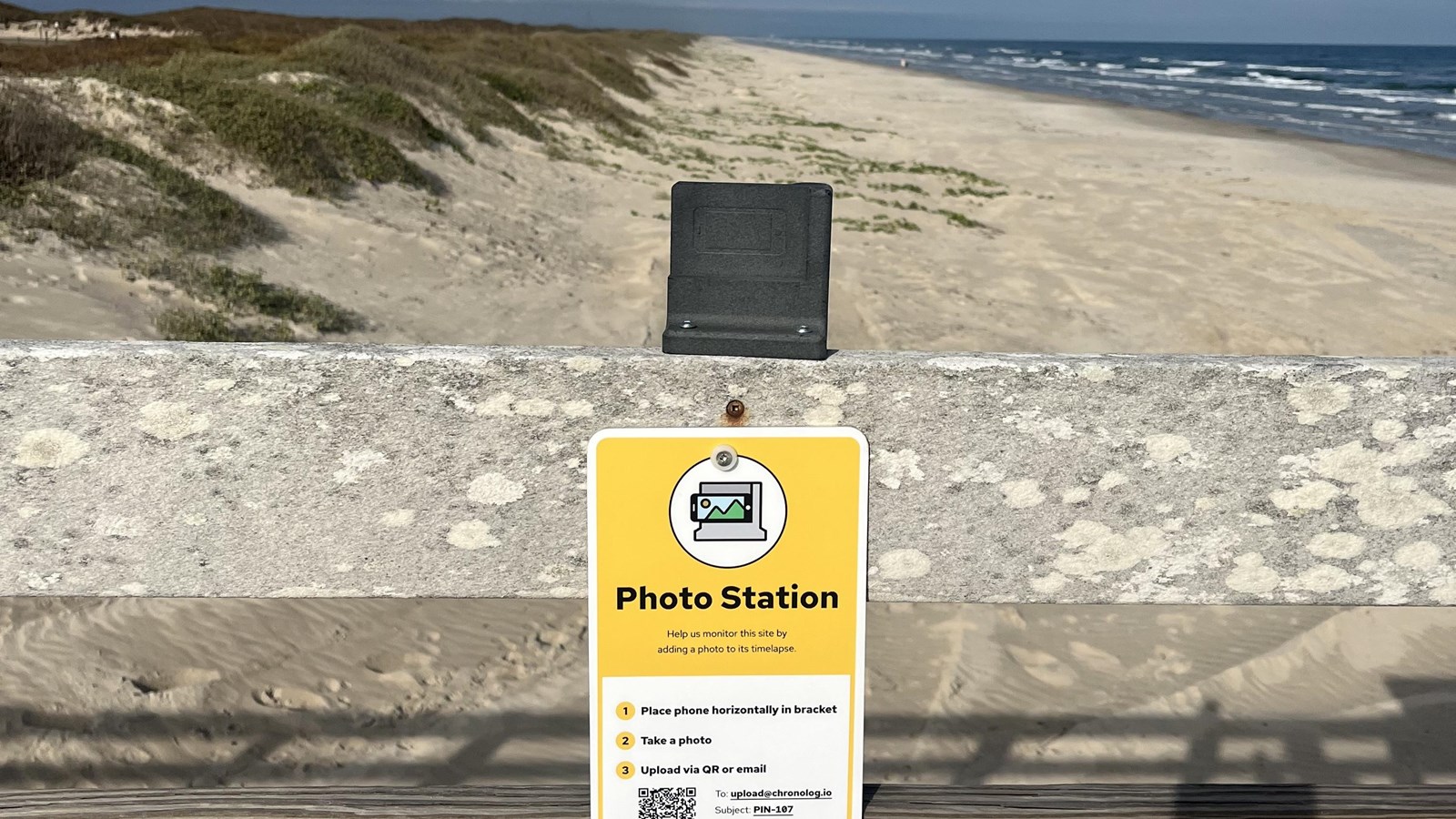 A photo monitoring station attached to a wooded railing. 