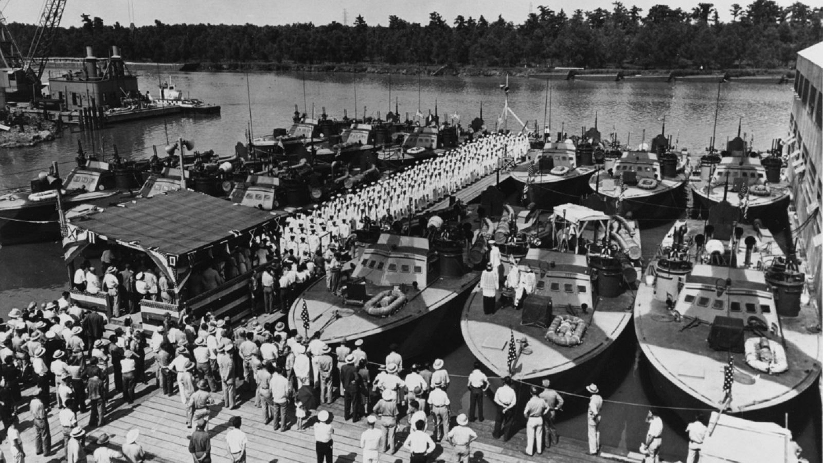a line of boats on a dock with a crowd of people