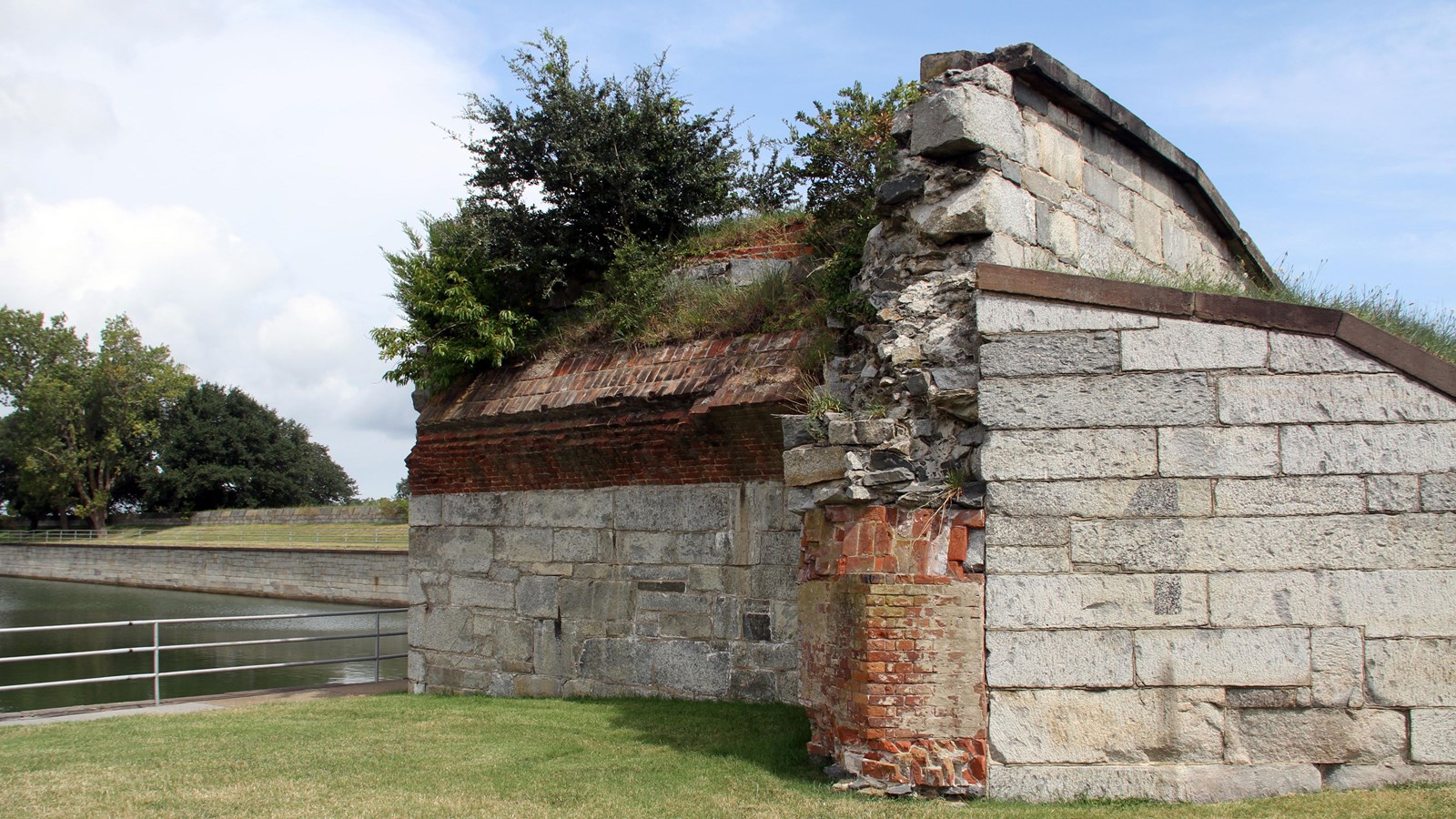 Remains of a masonry battery and magazine stand along a fort moat.