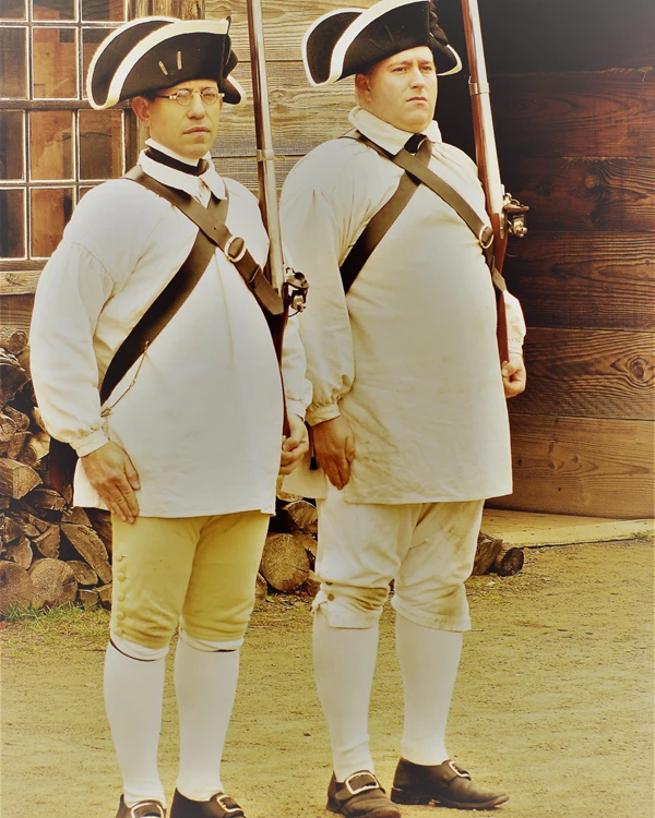 An image of two men standing next to each other. They are ridged and hold muskets at the shoulder.
