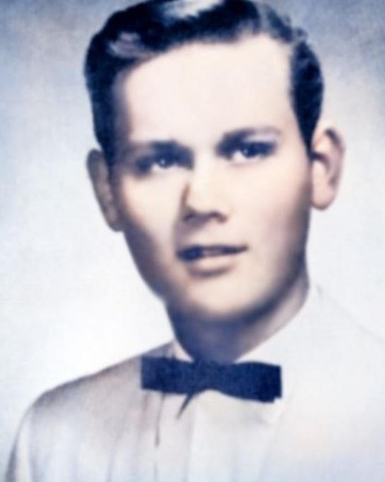 Young man in a dress shirt with a black bow tie posing for a picture. 