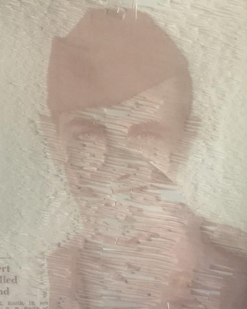 Young man in military uniform and hat smiling. 