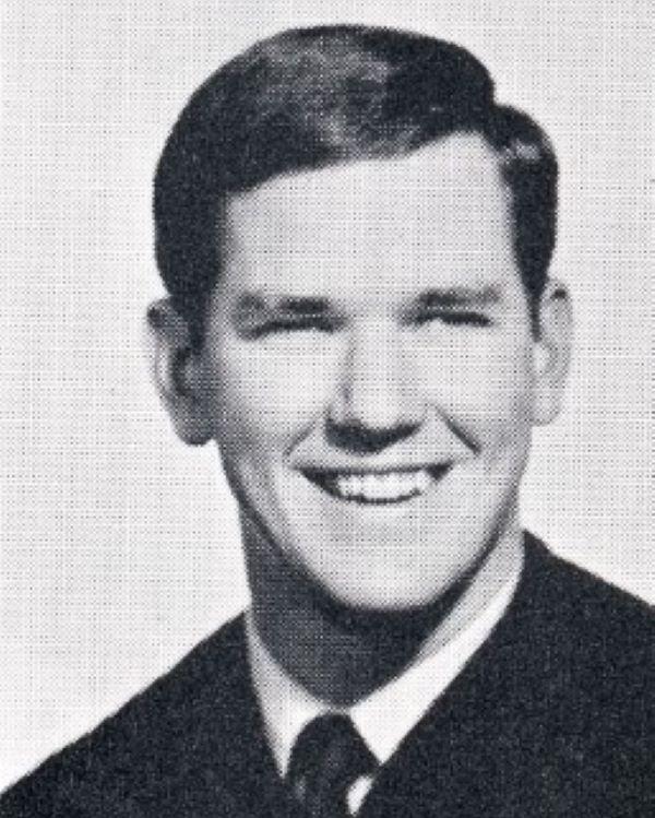 Young man wearing a suit and smiling for a photo. 