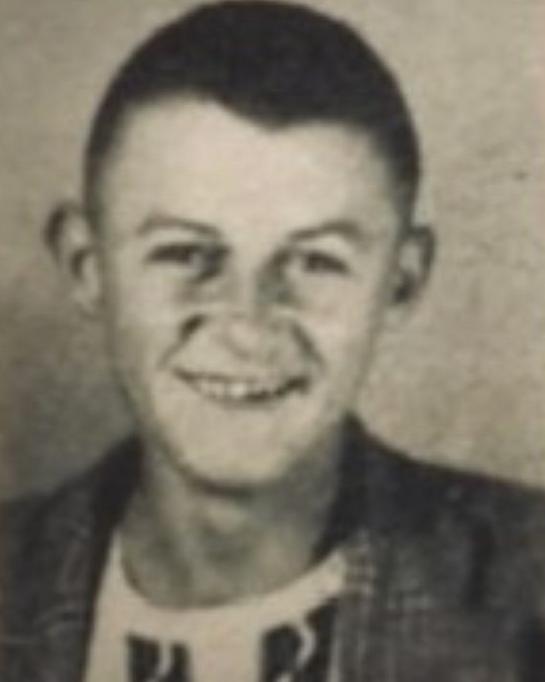 Young boy wearing a sweater and a jacket smiling for a photo. 