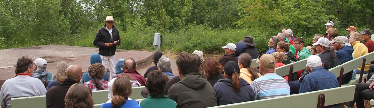 Tribal member addresses crowd seating on benches