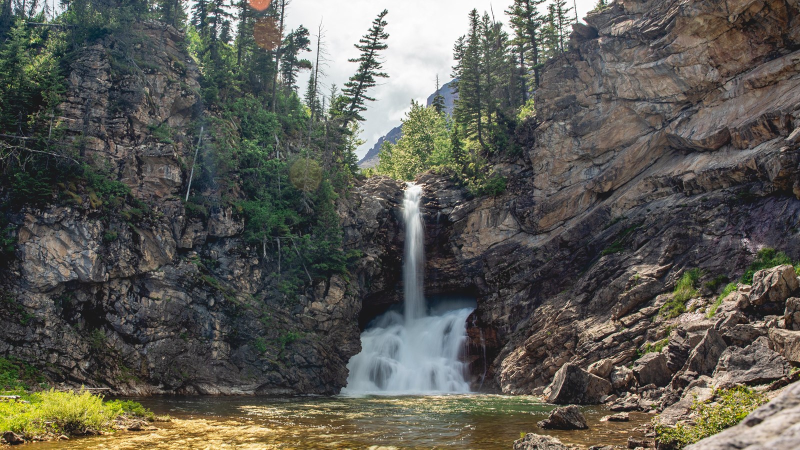 A large waterfall surrounded by rocks and trees. 