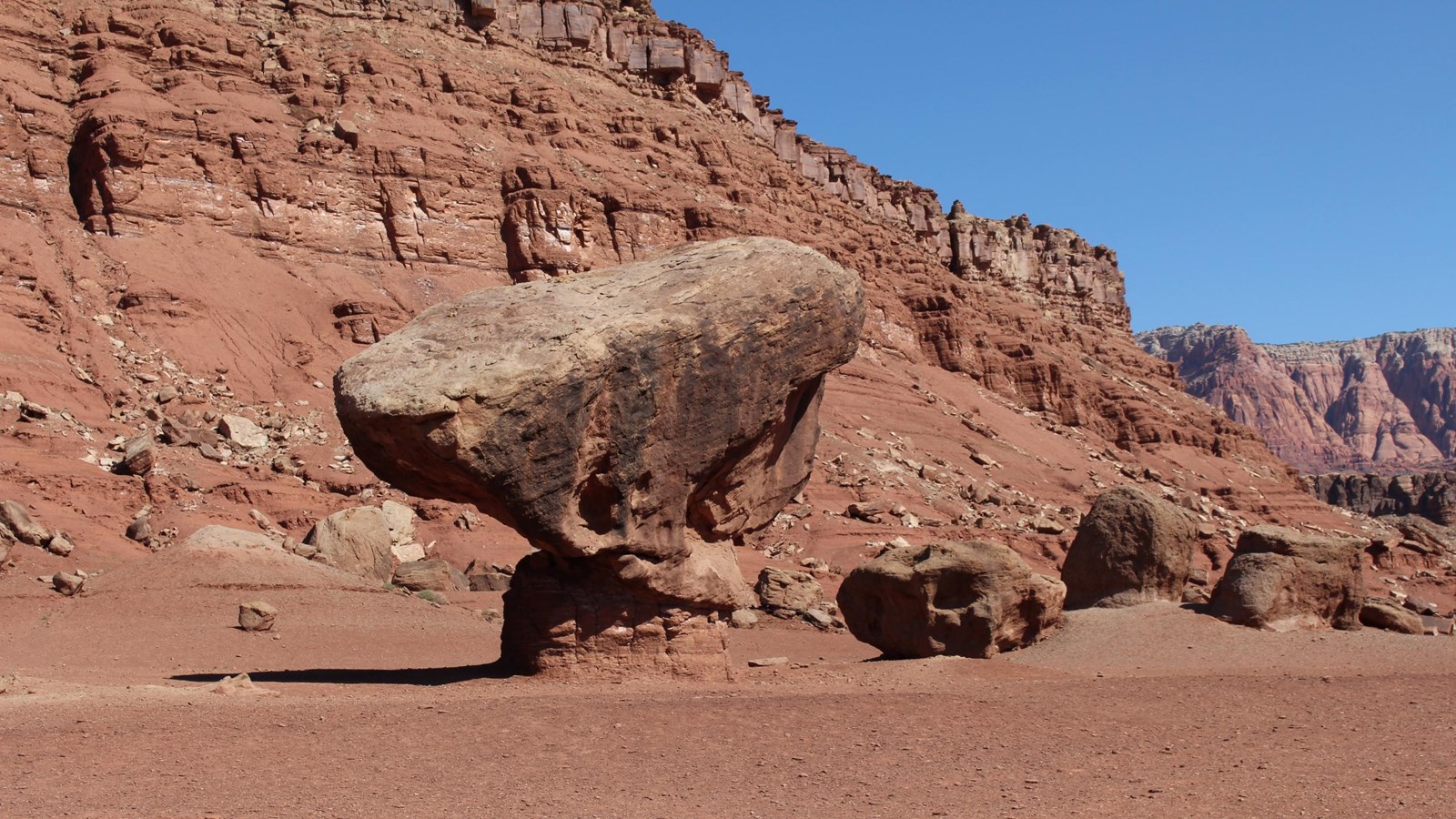Large bolder balanced on top on small compressed rock.