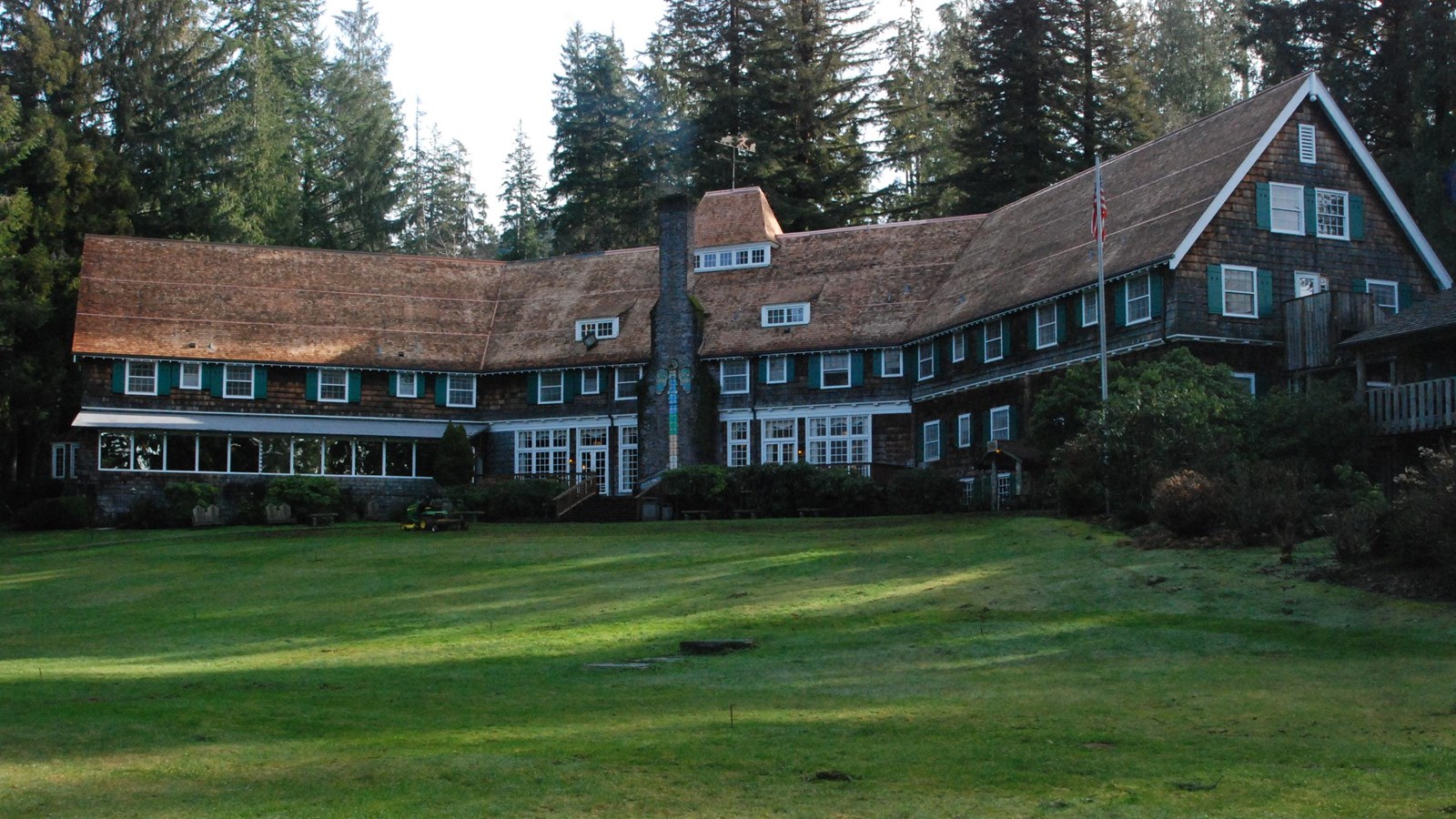A large wooden lodge building with a sprawling lawn.