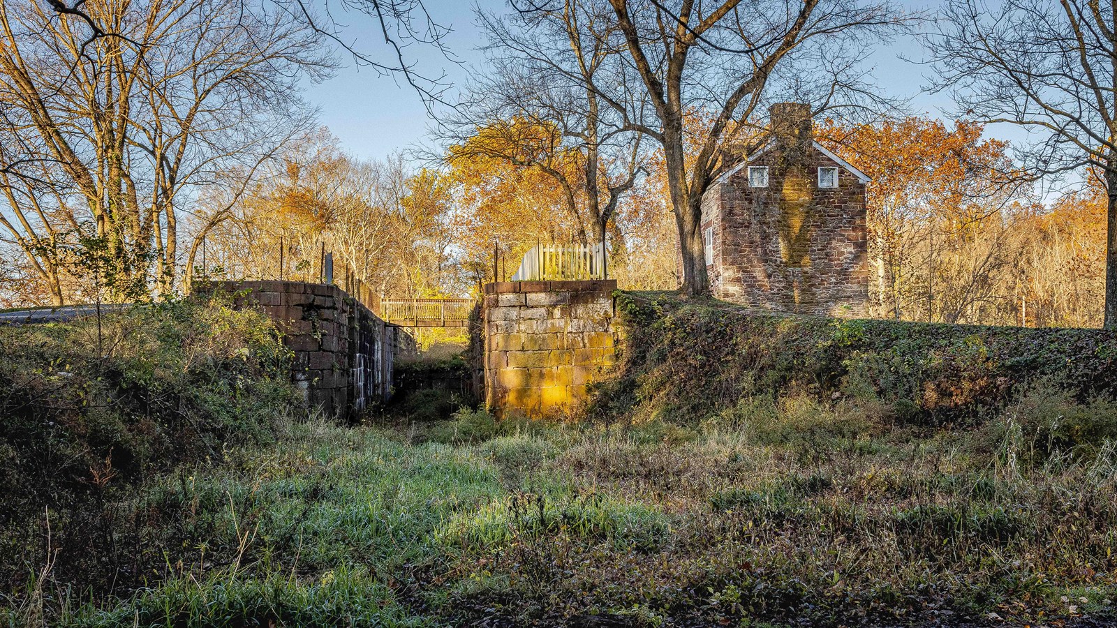 A lock and lockhouse sit surrounded by fall leaves. 