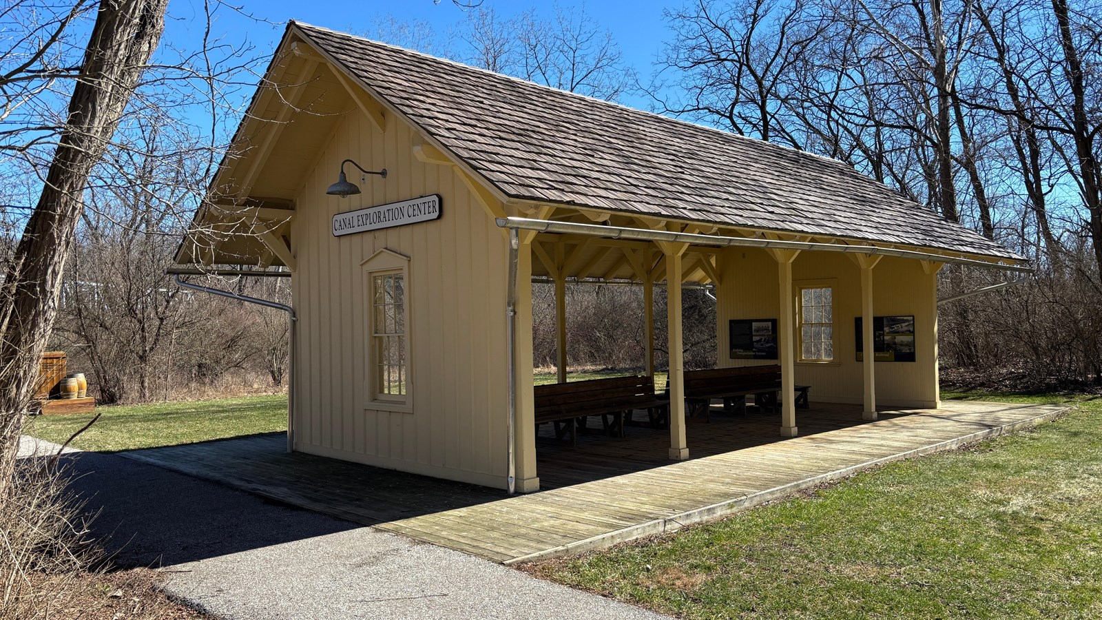 Yellow building with open sides and benches, with white sign that reads, 