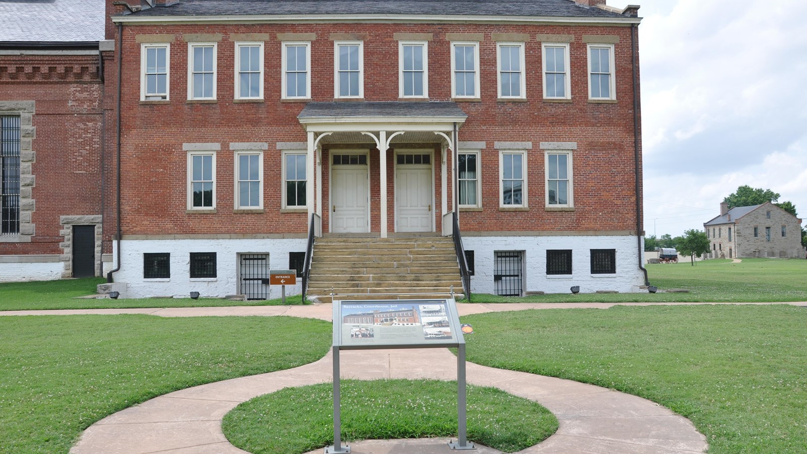 Wayside in front of a red brick building with a stone stairs leading to a porch.