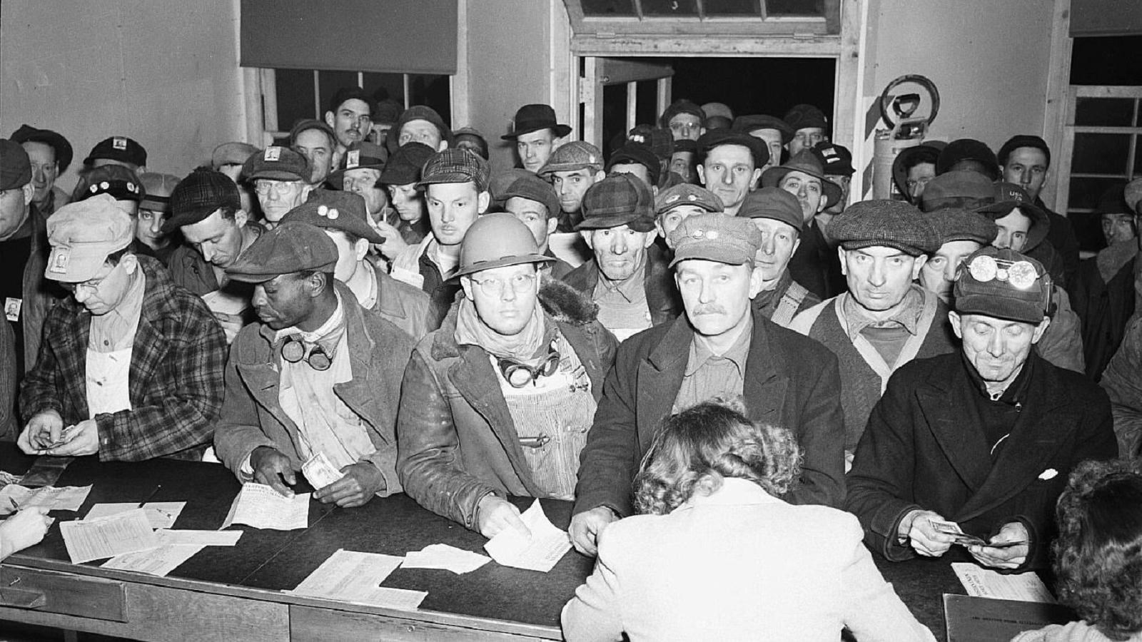 group of men at counter waiting for paychecks