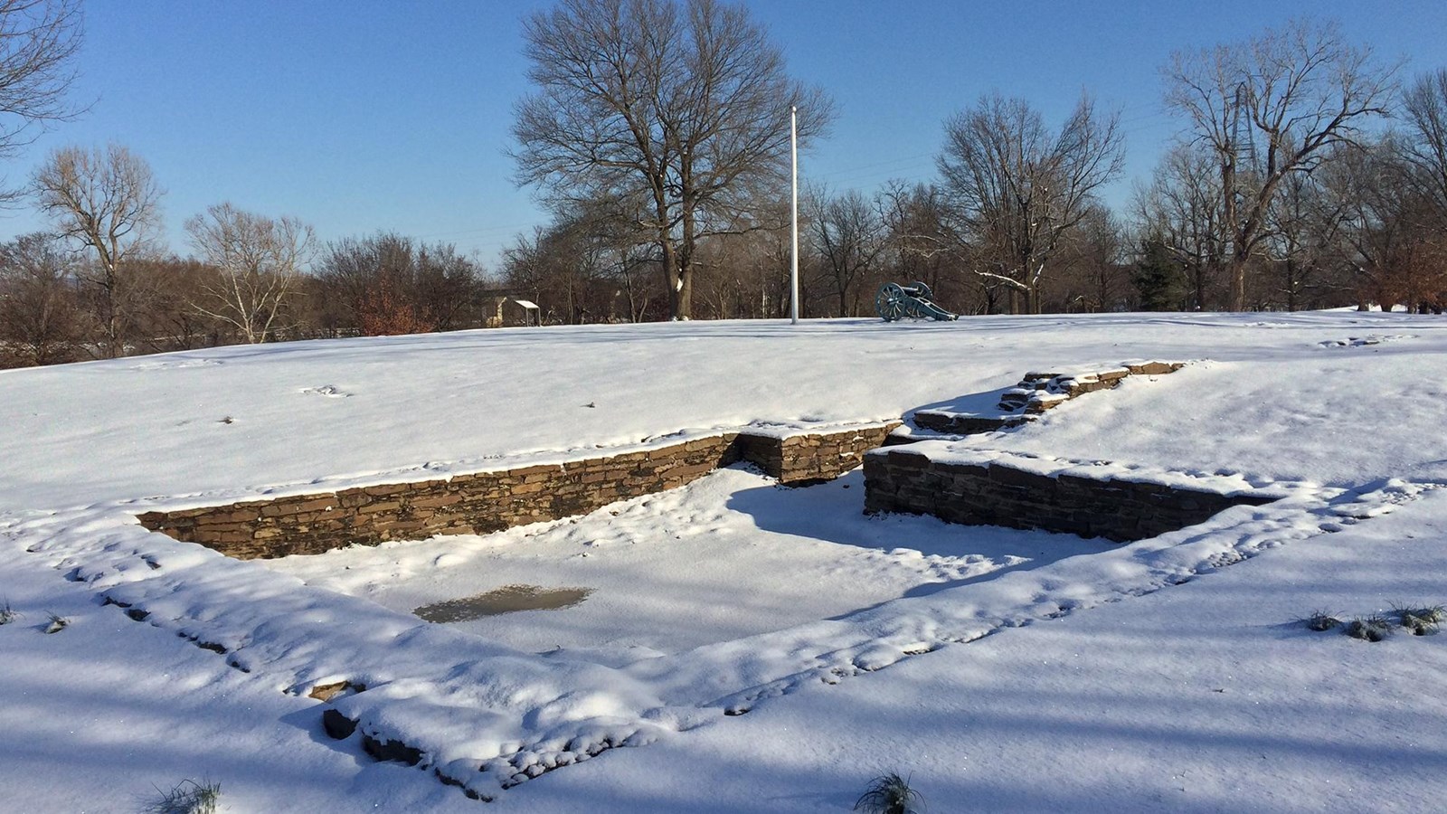 Snow covers the rectangular stone blockhouse foundation. On a clear winter morning.