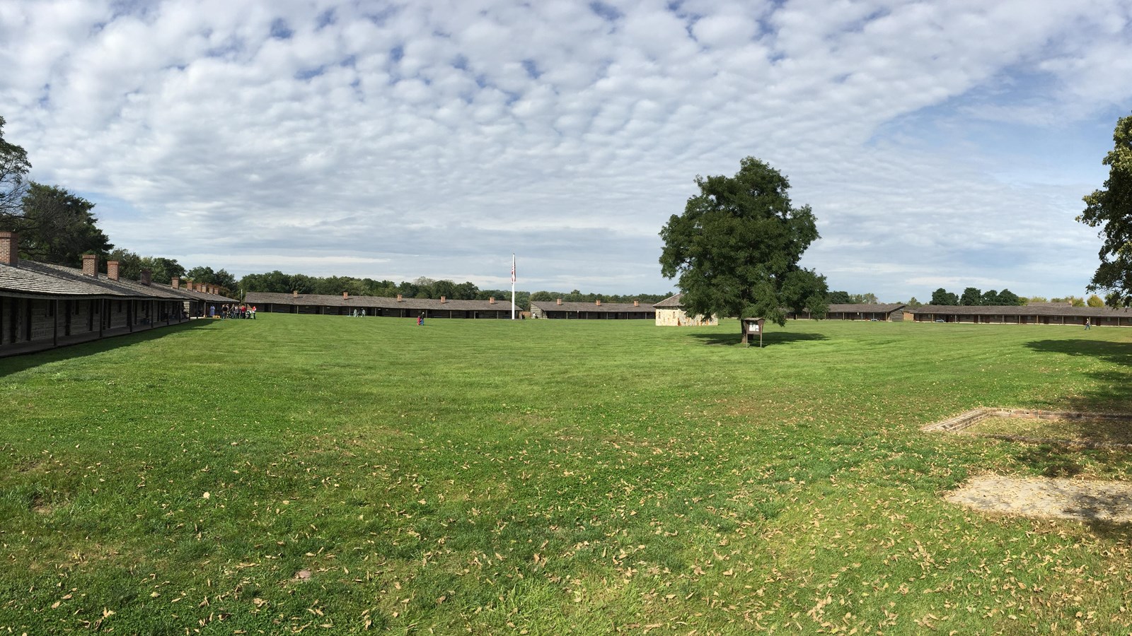 wooden fort buildings arranged in a square around a large grass field