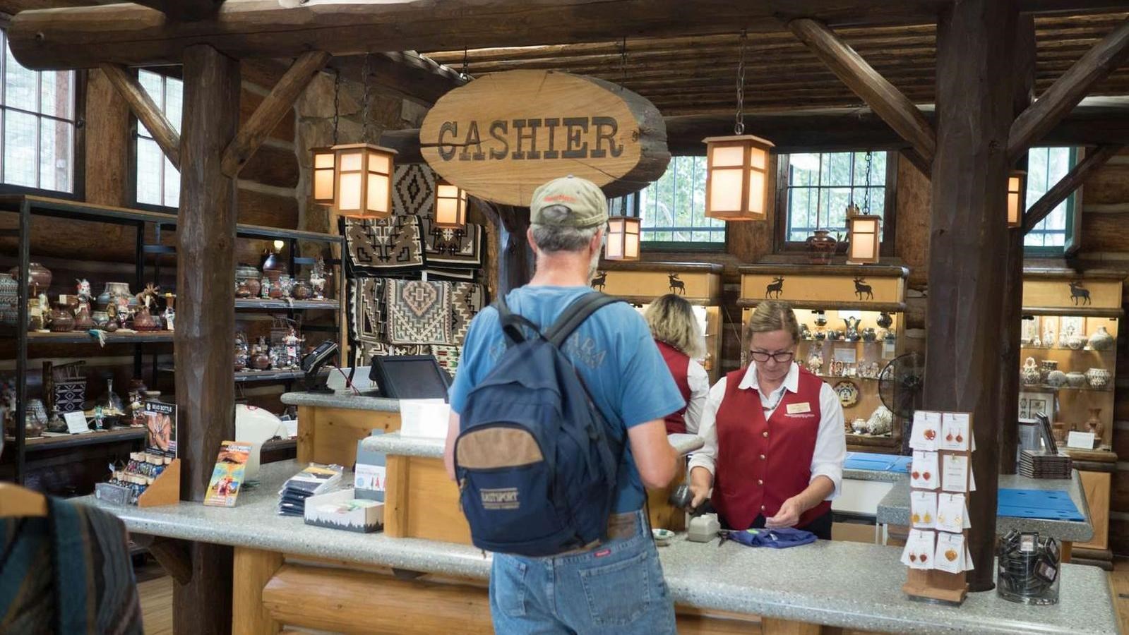 A person checks out at a counter in the middle of a large gift shop with exposed wood highlights