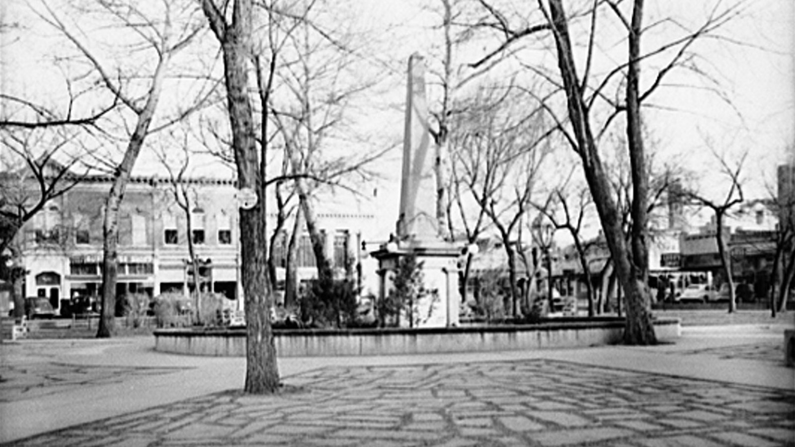 Photo of Santa Fe Plaza, with an obelisk monument in the center, surrounded by buildings. LOC photo