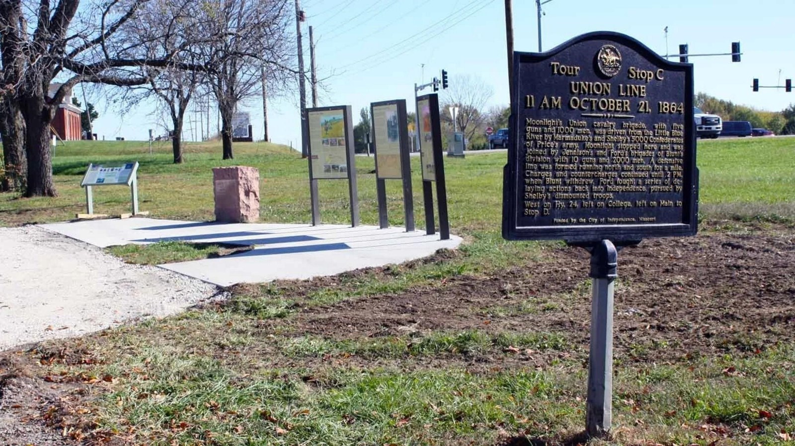 A brown sign sits on a post in a grassy area.