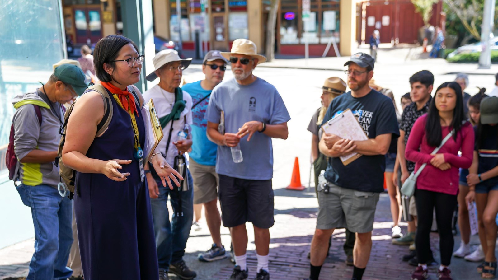Tour guide speaking to a diverse group of people. The scene is set on a sunny day.