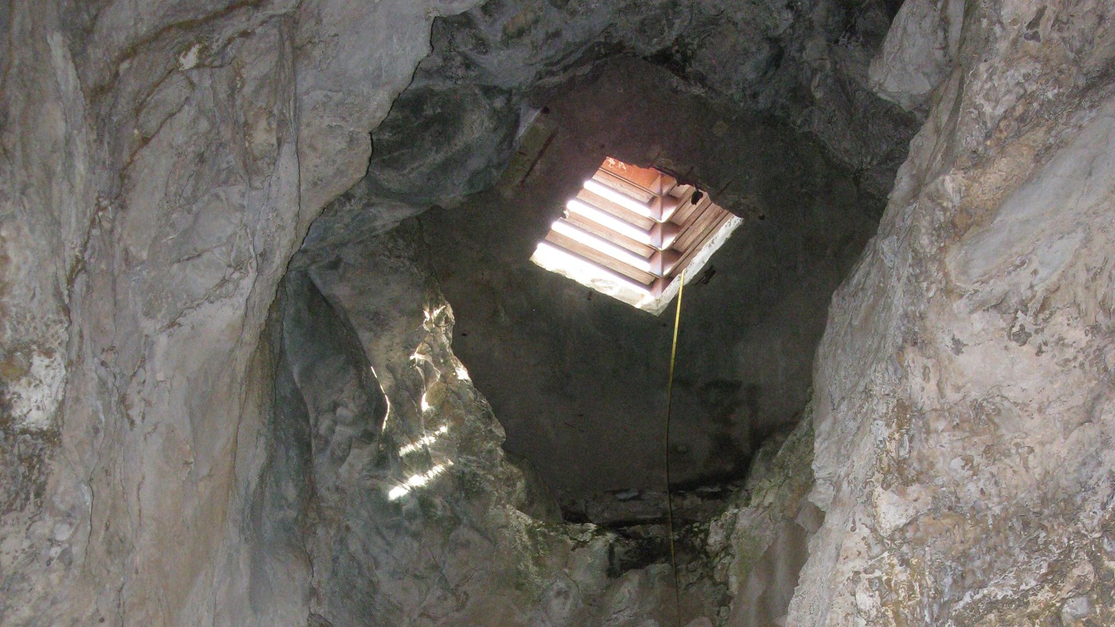 Light spills through a square hole above the viewer into the cavern below.