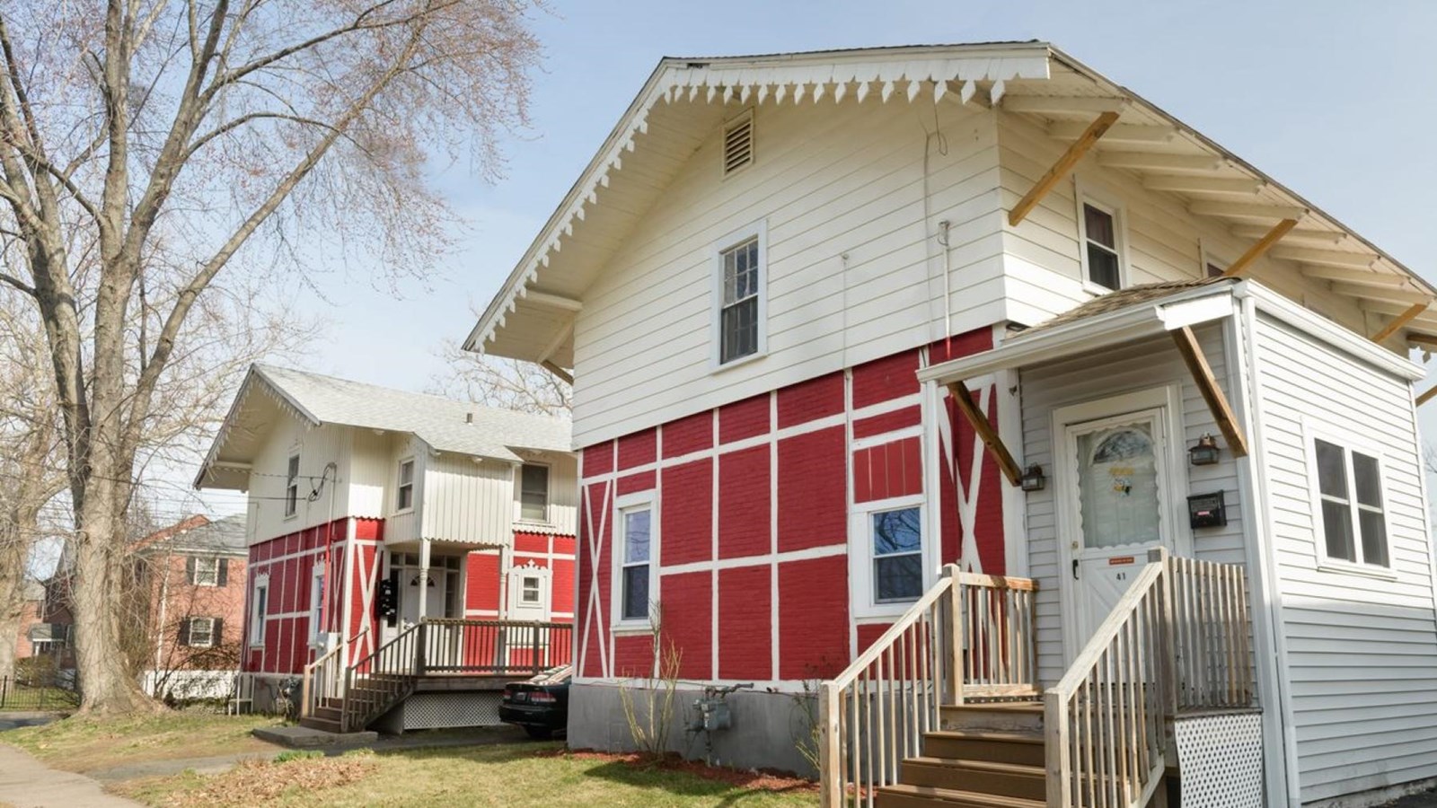 A two story, red and white house with a gabled metal roof and decorative bargeboard.