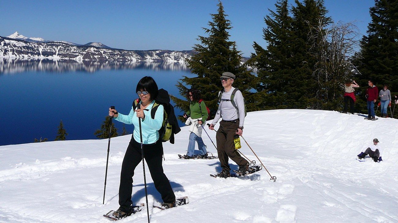 People snowshoeing with Crater Lake in the background.