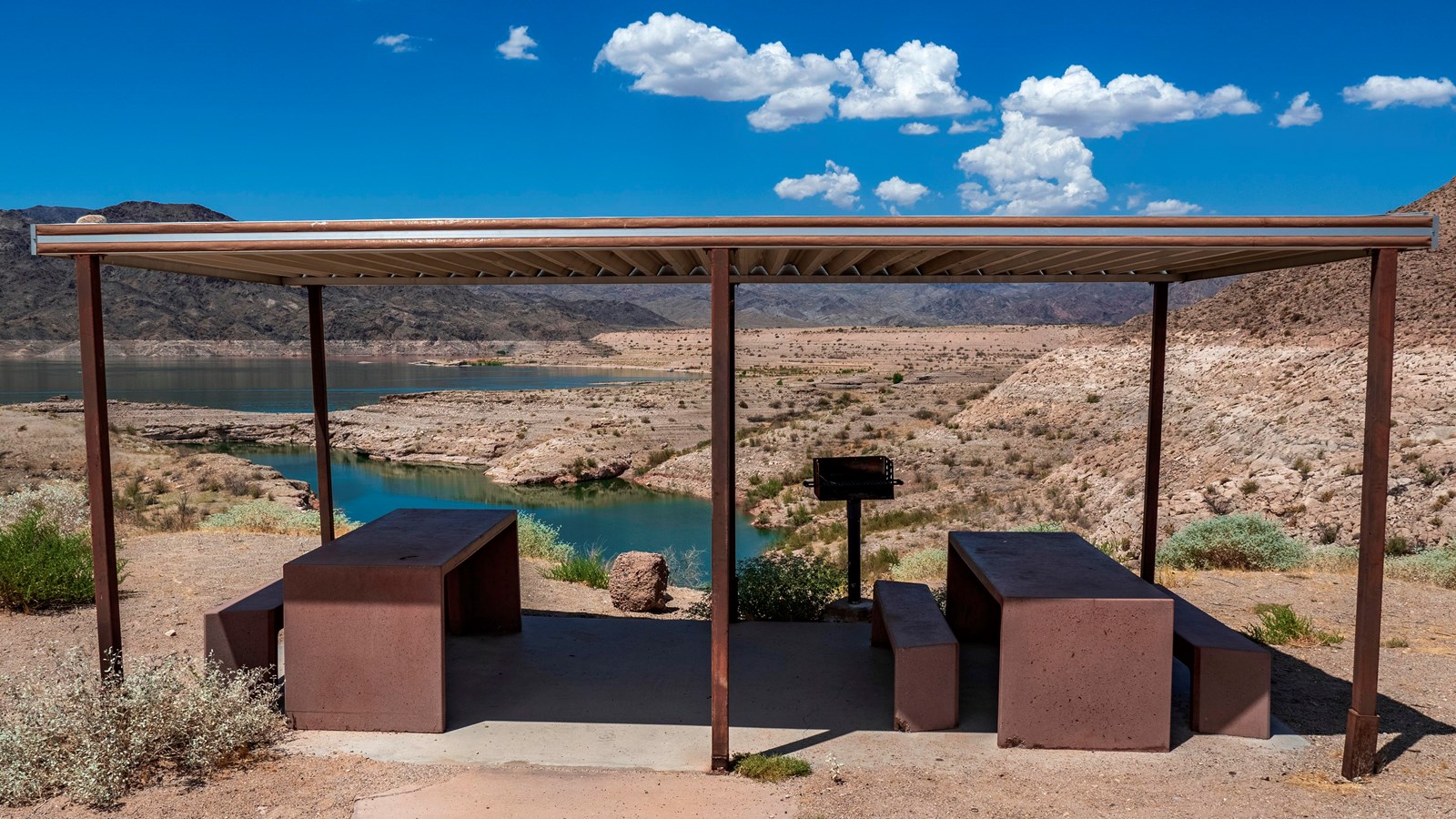 A view of a picnic area over a body of water and mountainous landscape
