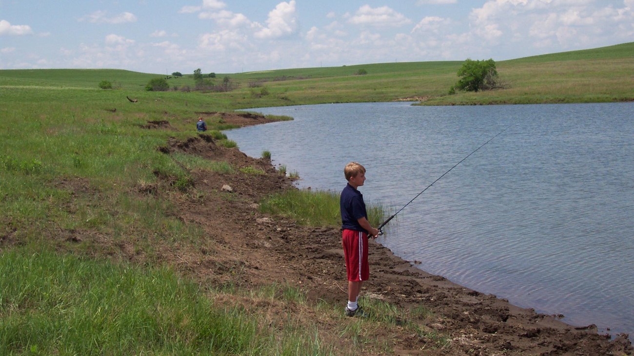 child with fishing pole by pond