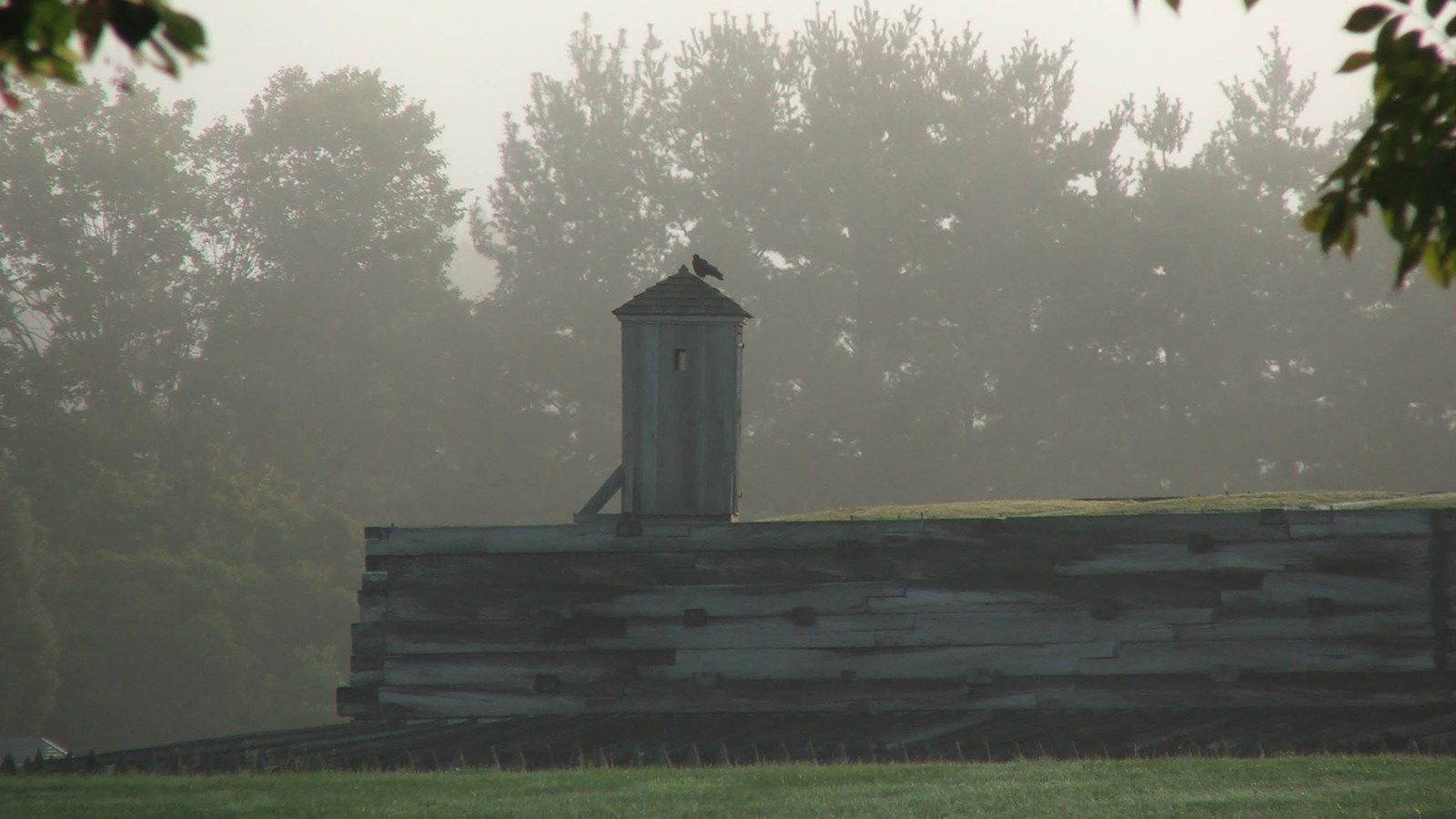 Fog encloses a wall of the fort. A sentry box can be seen popping out from the top of it. 