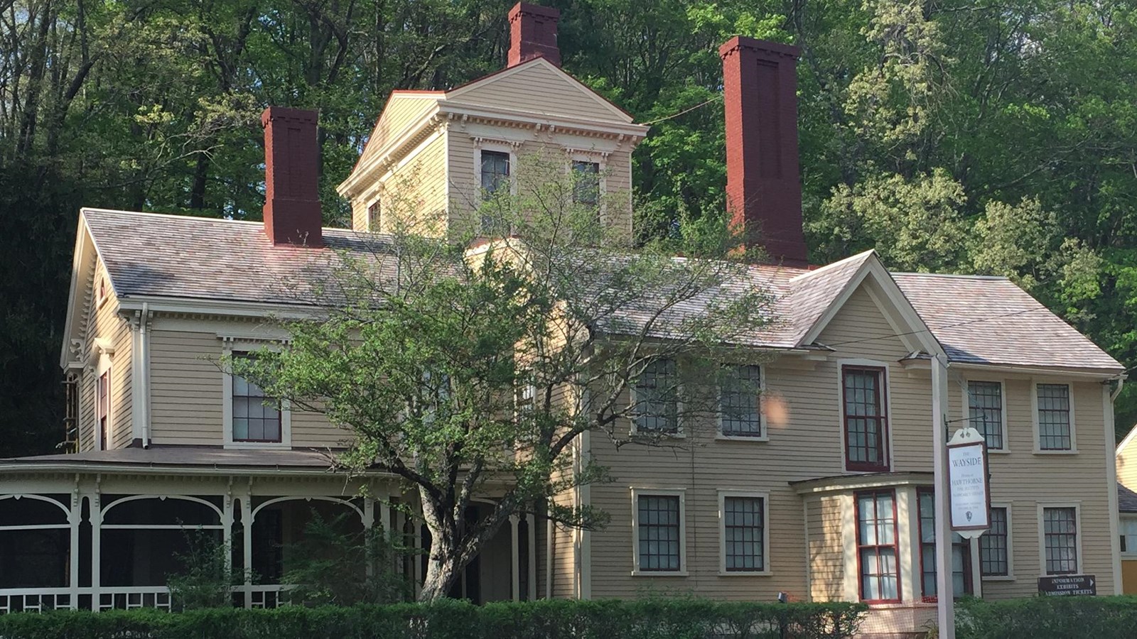 Two story house with pale yellow wooden siding. A three story tower on the back.