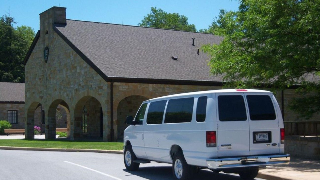 A white van by a stone building.