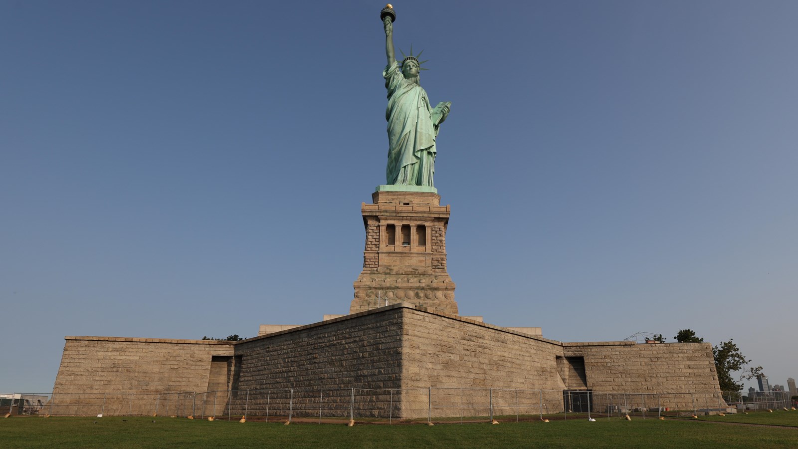 A green statue stands on top a brown stone pedestal.