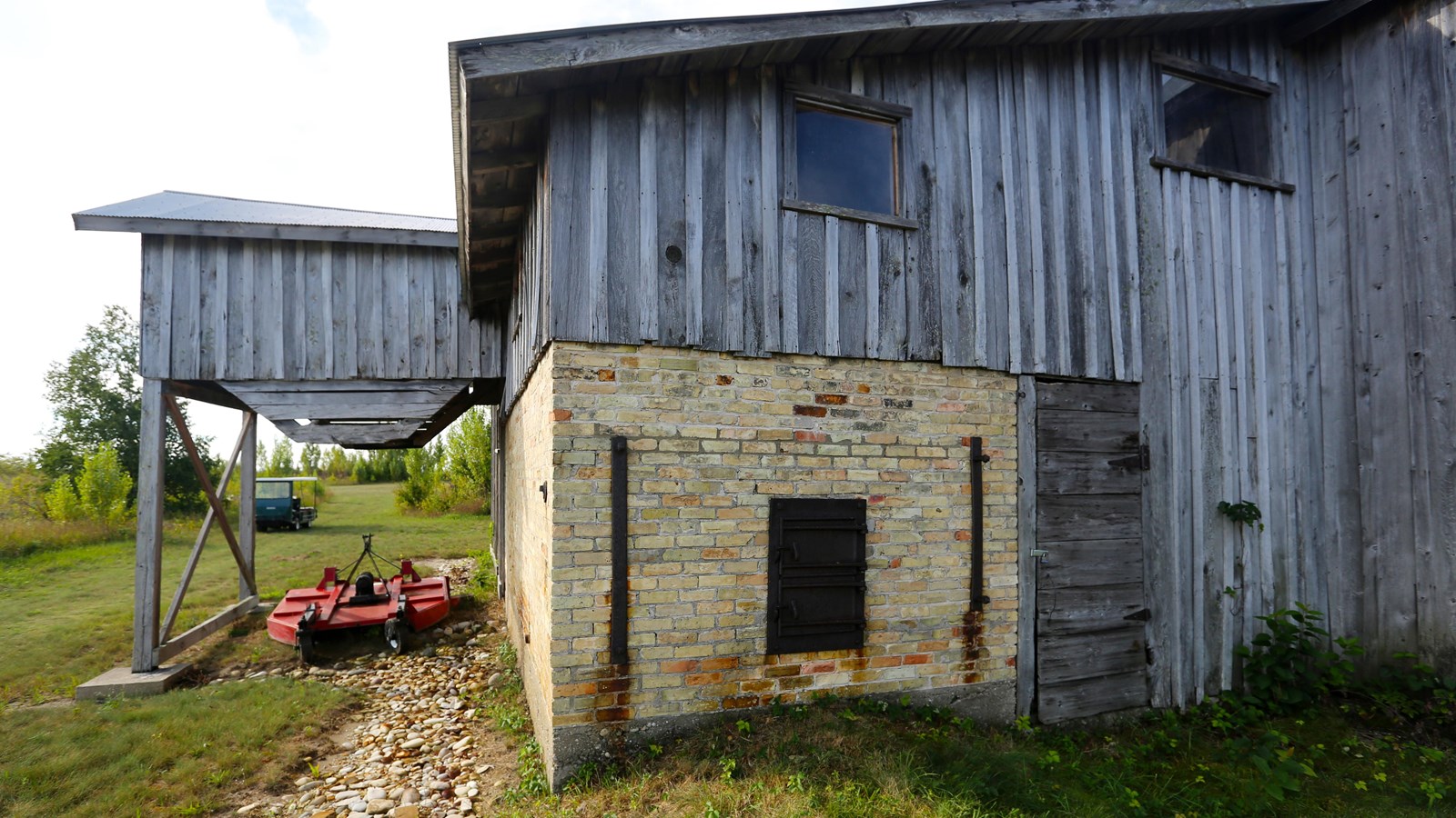 Long, 2-story vertical wooden plank structure with a corrugated metal gable roof