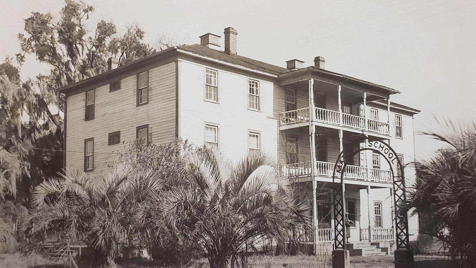 A multistory white building with porch.