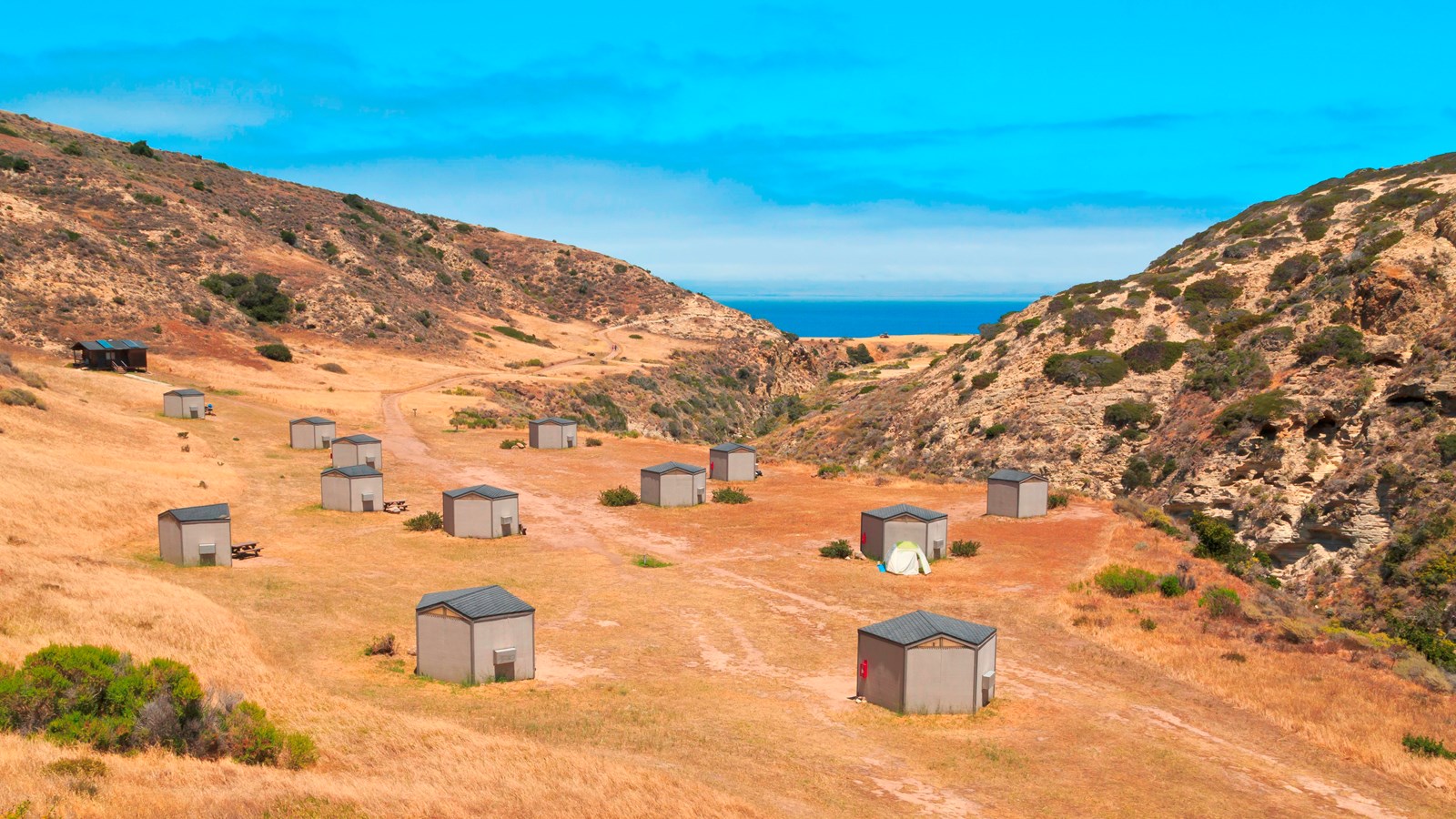 Wooden wind shelters in canyon overlooking ocean.