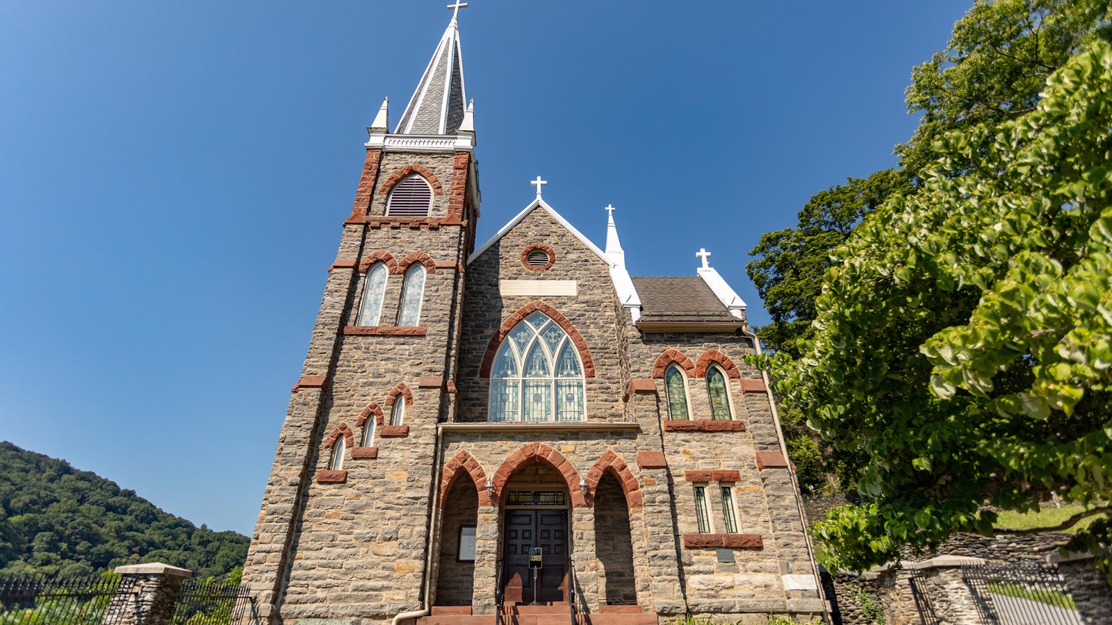 A stone church with pointed steeple and tall windows.