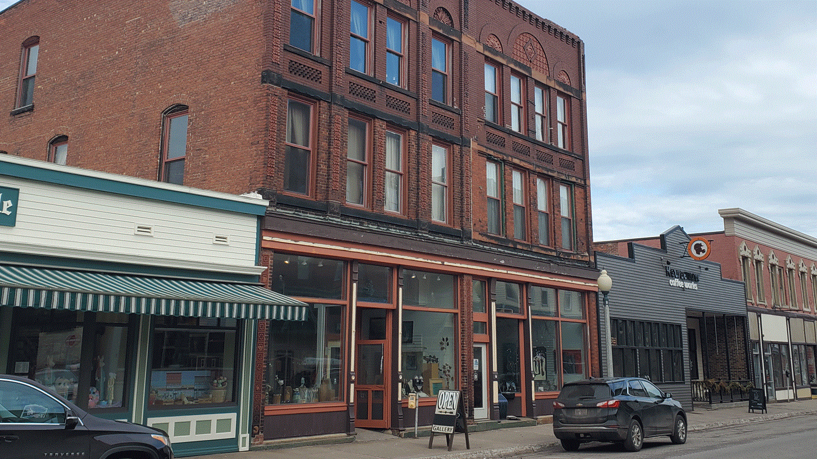 Three story red brick building with tall display windows on the first floor.